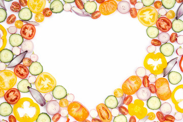Heart frame made of bright colorful vegetables with copy space. Salad ingredients, tomatoes cucumber peppers onions cut on white, top view, selective focus
