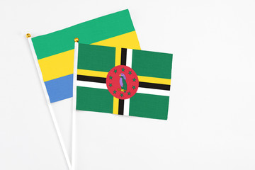 Dominica and Gabon stick flags on white background. High quality fabric, miniature national flag. Peaceful global concept.White floor for copy space.