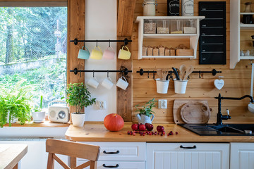 Vintage rustic interior of kitchen with white wooden  furniture, wooden wall and rustical decor....