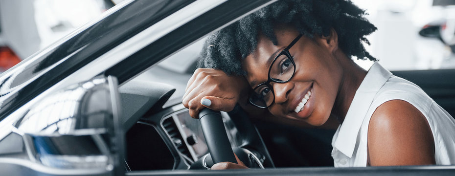 Cheerful Smile. Young African American Woman Sits Inside Of New Modern Car