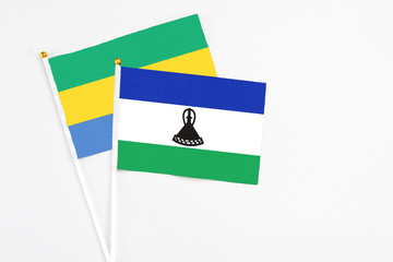 Lesotho and Gabon stick flags on white background. High quality fabric, miniature national flag. Peaceful global concept.White floor for copy space.