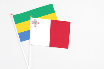 Malta and Gabon stick flags on white background. High quality fabric, miniature national flag....