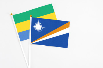 Marshall Islands and Gabon stick flags on white background. High quality fabric, miniature national flag. Peaceful global concept.White floor for copy space.