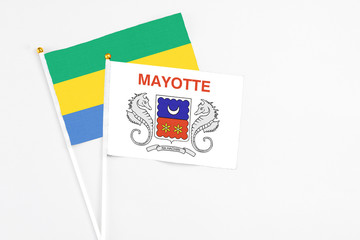 Mayotte and Gabon stick flags on white background. High quality fabric, miniature national flag. Peaceful global concept.White floor for copy space.