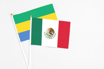 Mexico and Gabon stick flags on white background. High quality fabric, miniature national flag. Peaceful global concept.White floor for copy space.