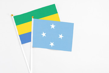 Micronesia and Gabon stick flags on white background. High quality fabric, miniature national flag. Peaceful global concept.White floor for copy space.