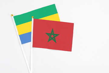Morocco and Gabon stick flags on white background. High quality fabric, miniature national flag. Peaceful global concept.White floor for copy space.