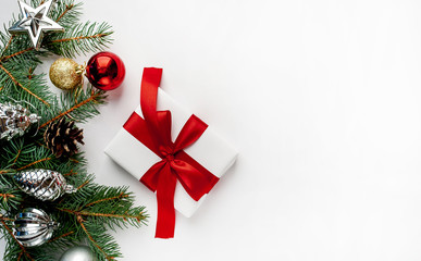 Christmas composition on a white background with white gift boxes, with a red ribbon with fir branches, toys, copy space for your congratulations