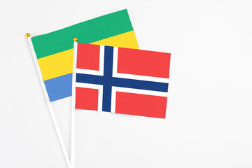 Norway and Gabon stick flags on white background. High quality fabric, miniature national flag....