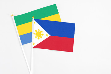Philippines and Gabon stick flags on white background. High quality fabric, miniature national flag. Peaceful global concept.White floor for copy space.