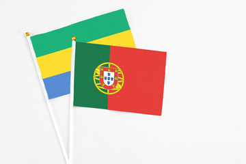 Portugal and Gabon stick flags on white background. High quality fabric, miniature national flag. Peaceful global concept.White floor for copy space.