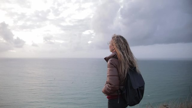 Portrait of young woman teenager traveler in glass on coast of normand.