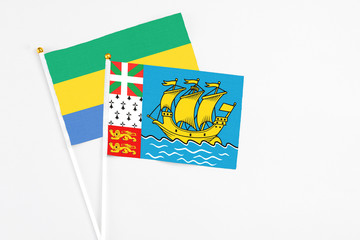 Saint Pierre And Miquelon and Gabon stick flags on white background. High quality fabric, miniature...