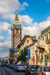 Fototapeta na wymiar Piazza Clock Tower In Batumi. European Historical Buildings And Stone Pavement In The City Centre In Resort Town. Georgian Architecture Landmark. Tourist Place.