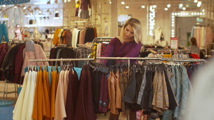 Woman sorts things out on a hanger in a store