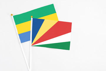 Seychelles and Gabon stick flags on white background. High quality fabric, miniature national flag. Peaceful global concept.White floor for copy space.