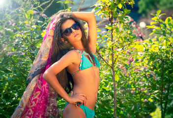 Portrait of beautiful young brown teenager model with poreo, in summer colorful swimsuit posing on...