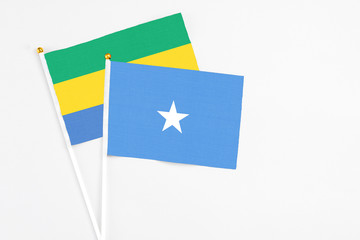 Somalia and Gabon stick flags on white background. High quality fabric, miniature national flag. Peaceful global concept.White floor for copy space.