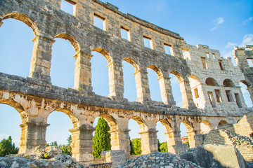 Ancient heritage in Pula, Istria, Croatia. Arches of monumental Roman arena. Detail of historic amphitheater, wide angle view of walls on blue sky background.