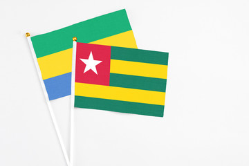 Togo and Gabon stick flags on white background. High quality fabric, miniature national flag. Peaceful global concept.White floor for copy space.