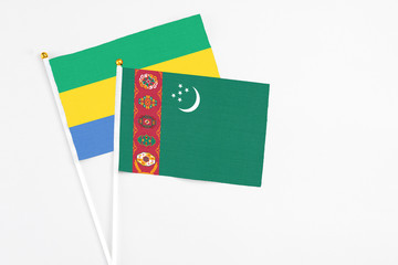 Turkmenistan and Gabon stick flags on white background. High quality fabric, miniature national...