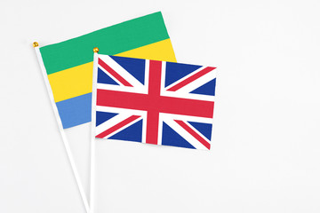 United Kingdom and Gabon stick flags on white background. High quality fabric, miniature national flag. Peaceful global concept.White floor for copy space.