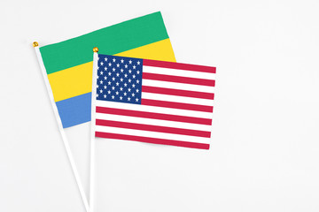 United States and Gabon stick flags on white background. High quality fabric, miniature national flag. Peaceful global concept.White floor for copy space.