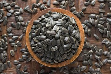 shelled sunflower seeds in wooden bowl, top view.