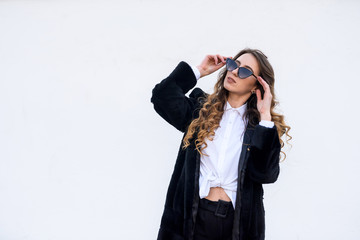 Fashion woman in fur coat and sunglasses posing outdoors