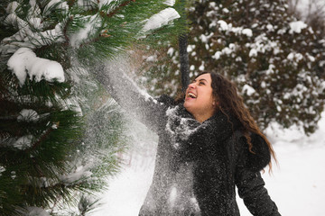 A beautiful pregnant woman is playing outside in the snow