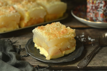 Cake with apples and coconut on a rustic plate on a wooden background