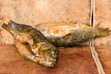 Hot smoked carp on old wooden boards.