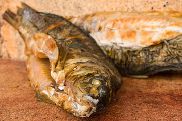 Hot smoked carp on old wooden boards.