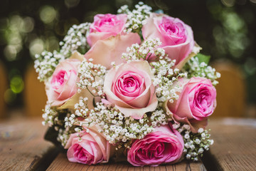 Wedding bouquet with pink roses on wooden table.