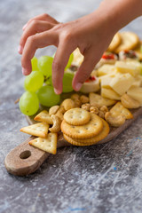 Variety of appetizers on a board with child's hand