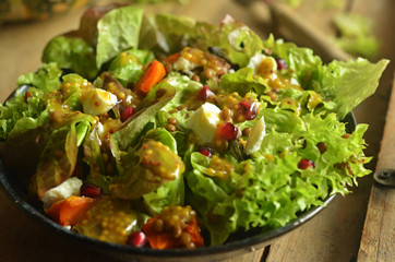 Salad with pumpkin, lentils and goat cheese in a blue bowl on a wooden background