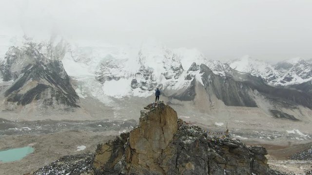 Hiker Man on Top of Kalapatthar Mountain Looking on Khumbu Icefall, Everest and Nuptse. Himalaya, Nepal. Aerial View. Drone is Orbiting