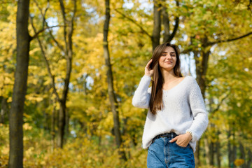 Fototapeta na wymiar Autumn landscape. Woman in casual wear posing in park with yellow leaves