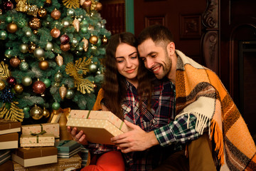Young couple with gifts near Christmas tree