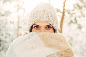 The girl wrapped herself in a knitted woolen scarf in nature in winter