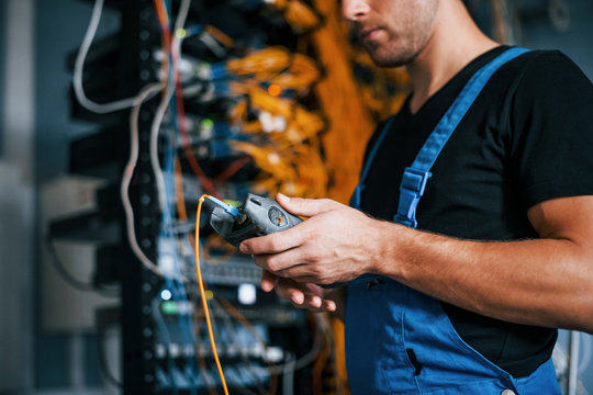 Young man in uniform have a job with internet equipment and wires in server room