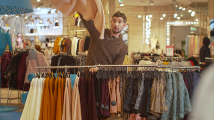 Guy sorts things out on a hanger in a store