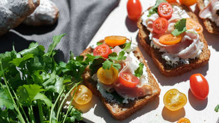 toasts with ham and tomatoes and greens on a gray background. 
