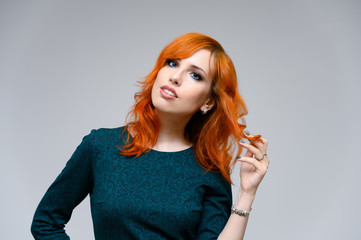 Portrait of a red-haired pretty girl with excellent makeup and bright curly hair on a white background. Beauty concept, sample of beautiful hairstyle and makeup with cosmetics.