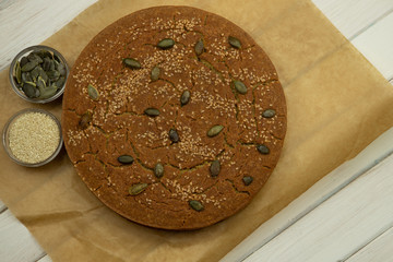 Homemade buckwheat flour and millet bread, pumpkin and sesame seeds, a sheet of paper. Healthy alternative food.