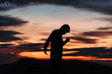 Obraz premium Silhouette of a man standing in front of the sunrise with his arms raised