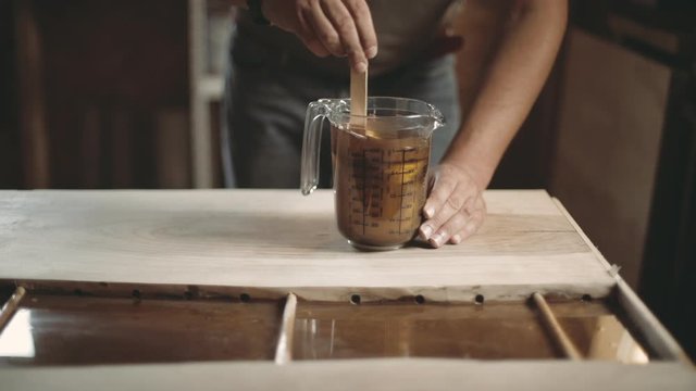 Carpenter mixing golden powder into epoxy resin