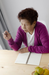 Asian senior woman  writing notebook at home, lifestyle concept.