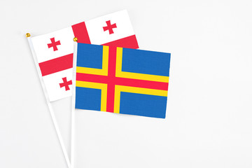 Aland Islands and Georgia stick flags on white background. High quality fabric, miniature national flag. Peaceful global concept.White floor for copy space.