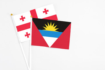 Antigua and Barbuda and Georgia stick flags on white background. High quality fabric, miniature national flag. Peaceful global concept.White floor for copy space.